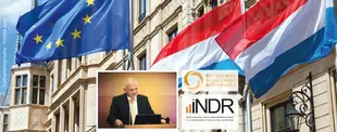 Das Bild zeigt EU- und Luxemburg-Flaggen vor einem historischen Gebäude, einen Redner am Pult und das Logo des INDR für soziale Unternehmensverantwortung.