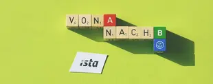Holzwürfel mit den Wörtern „VON A NACH B“ auf grünem Hintergrund. Ein ista-Logo liegt daneben, das blaue „B“-Würfel zeigt ein Smiley-Symbol.
