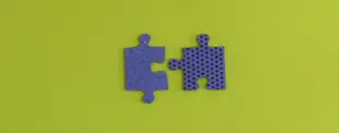 Zwei lila Puzzleteile liegen auf einem gelbgrünen Hintergrund. Ein Teil ist glatt, das andere hat eine perforierte Oberfläche.