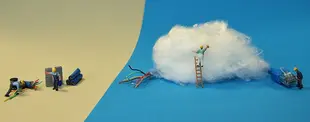 Miniaturfiguren arbeiten an einer symbolischen Darstellung der digitalen Transformation: Links klassische Verkabelung, rechts eine „Cloud“ mit Technikern auf einer Leiter.