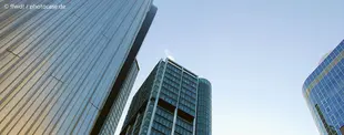 Das Bild zeigt moderne Hochhäuser aus der Froschperspektive vor einem klaren Himmel, symbolisierend Wachstum, Fortschritt und unternehmerische Exzellenz