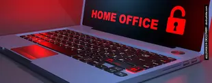 Ein Laptop mit rot beleuchteter Tastatur zeigt auf dem Bildschirm „HOME OFFICE“ und ein offenes Schloss-Symbol.