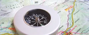 Das Bild zeigt einen silbernen Kompass auf einer detaillierten Landkarte, symbolisierend Orientierung und strategische Planung in der IT-Roadmap.