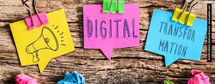 Drei bunte Sprechblasen-Notizen mit den Worten Digital, Transformation und einer Megafon-Zeichnung hängen mit Klammern an Holz, umgeben von zerknülltem Papier.