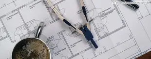 Das Bild zeigt einen Architekturplan mit einem Zirkel, einer Tasse Kaffee und einem Stift, symbolisierend die strategische Planung und Gestaltung in der Unternehmensarchitektur.