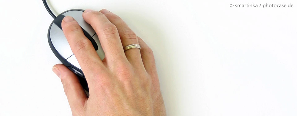 Eine Hand mit Ehering bedient eine kabelgebundene Computermaus auf weißem Hintergrund.