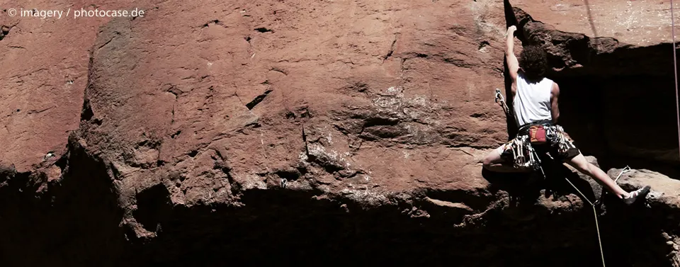 ChatGPT:  Das Bild zeigt eine Person beim Klettern an einer Felswand mit Kletterausrüstung. Es symbolisiert Herausforderung, Ausdauer und Zielstrebigkeit.