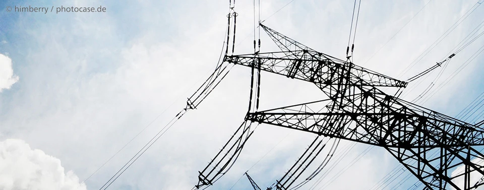 Das Bild zeigt einen großen Strommast mit Hochspannungsleitungen vor einem teils bewölkten Himmel.